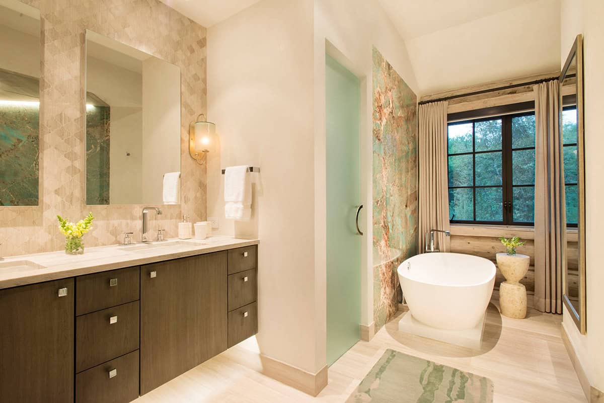 Bathroom with freestanding tub, green stone accent wall, and double vanity