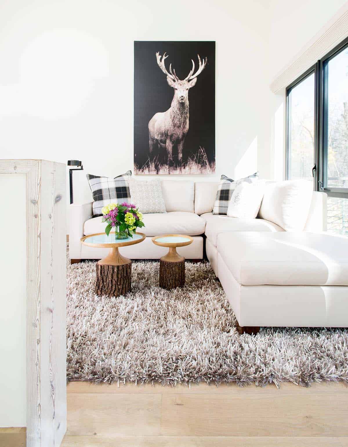 Living room with white sectional, shag rug, and stag artwork