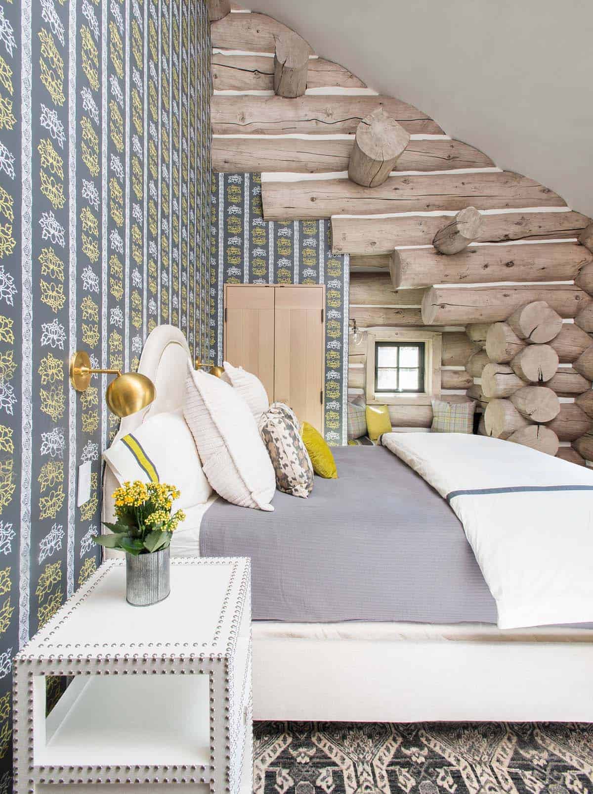 Bedroom with patterned wallpaper, log wall, and upholstered headboard