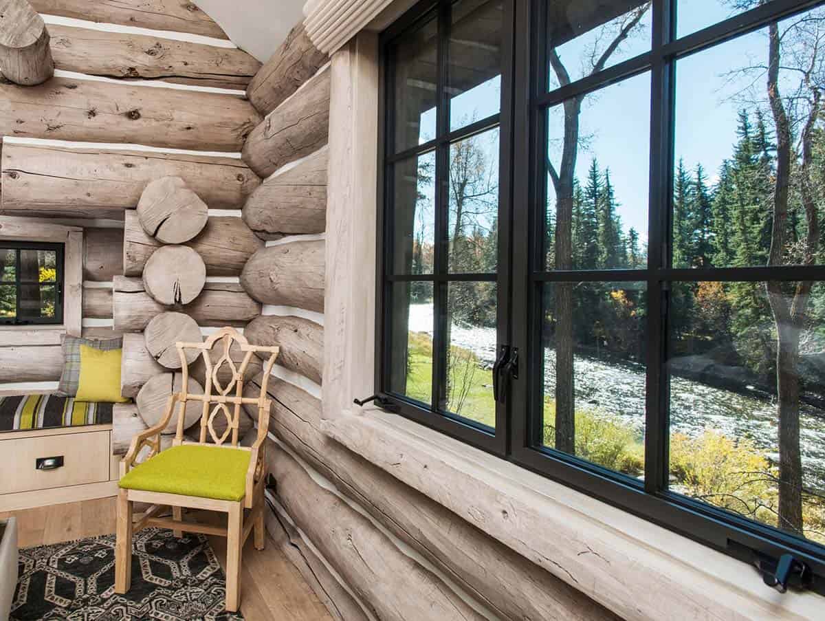 Guest bedroom corner detail with log walls and river view through large windows