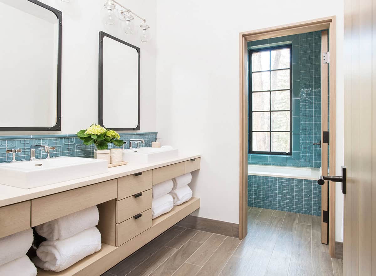 Bathroom vanity opening into a teal-tiled bath and shower area