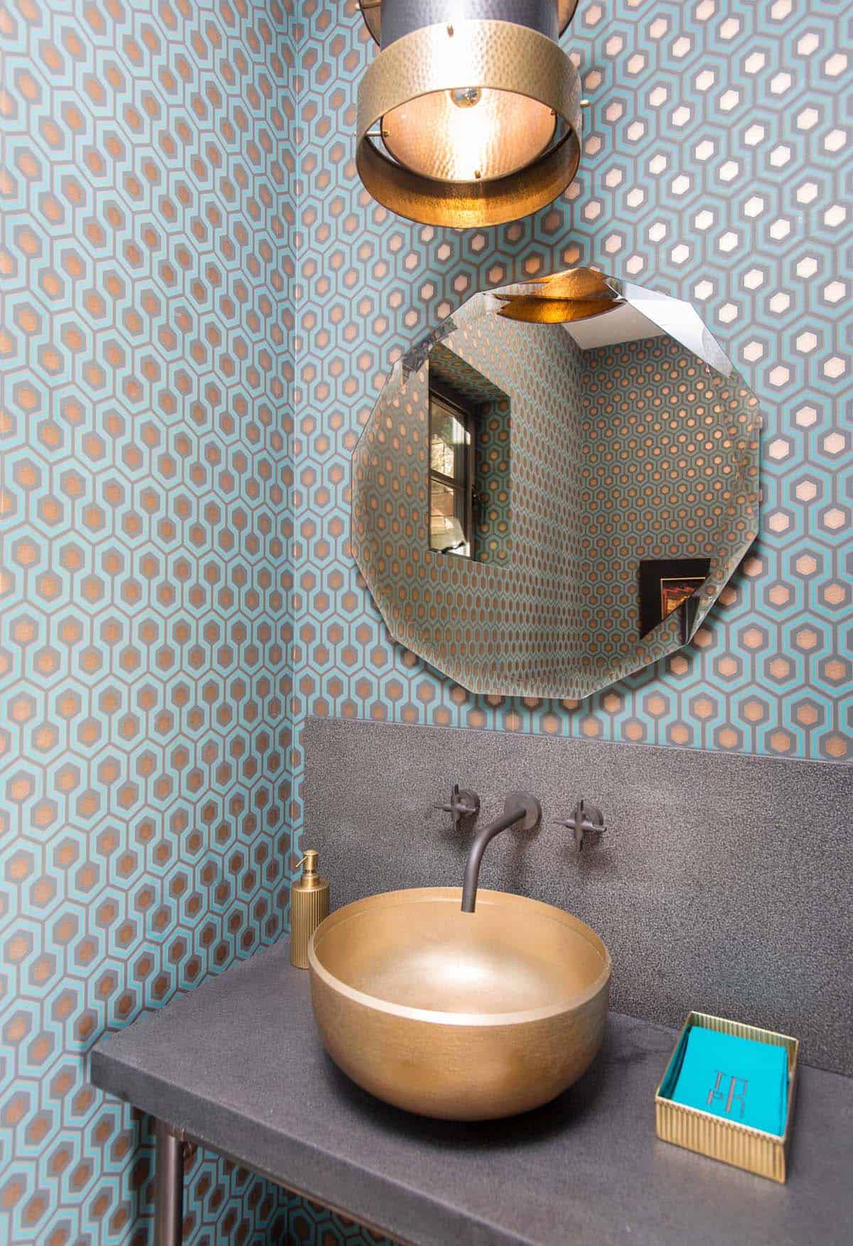Powder room with geometric wallpaper, gold vessel sink, and faceted mirror