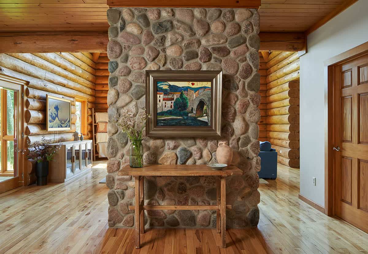 Entryway with round river-stone fireplace column, wood console table, and framed artwork