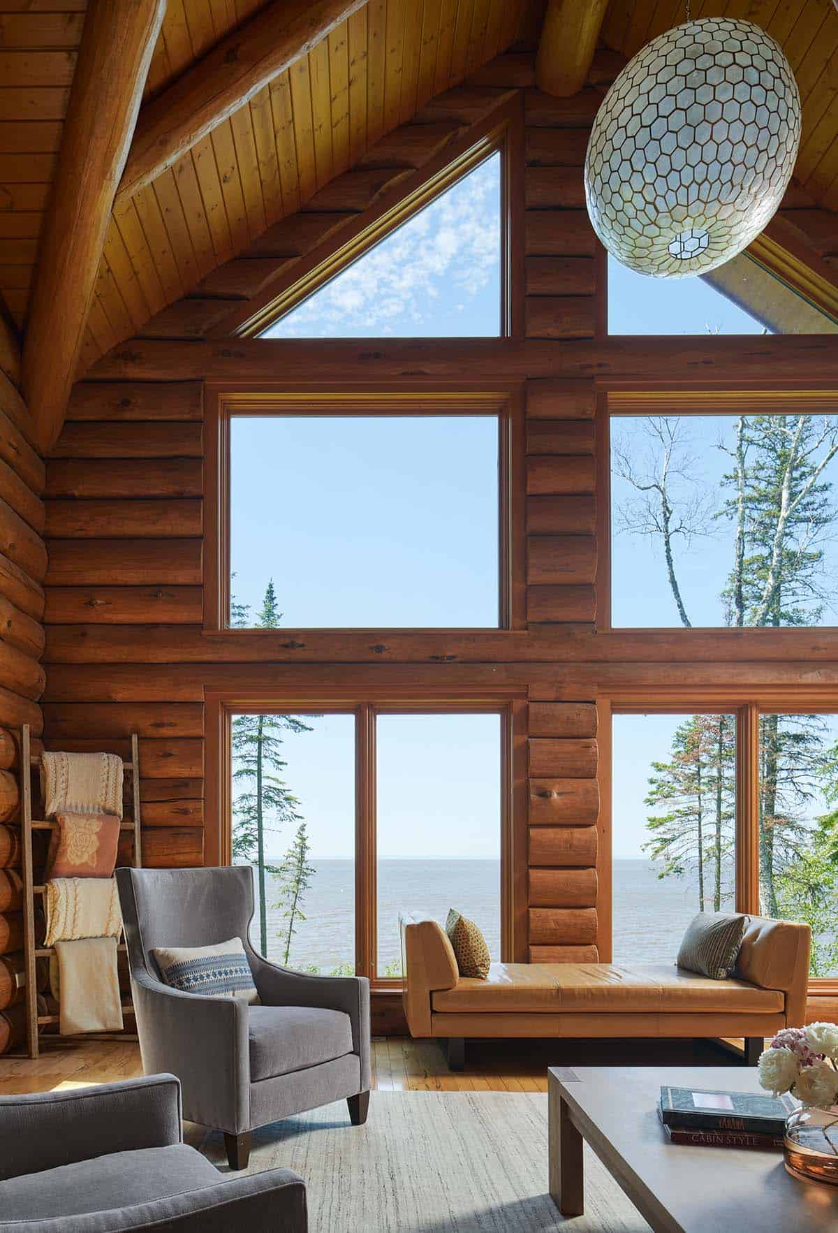 Vaulted log cabin living room with floor-to-ceiling windows overlooking Lake Superior