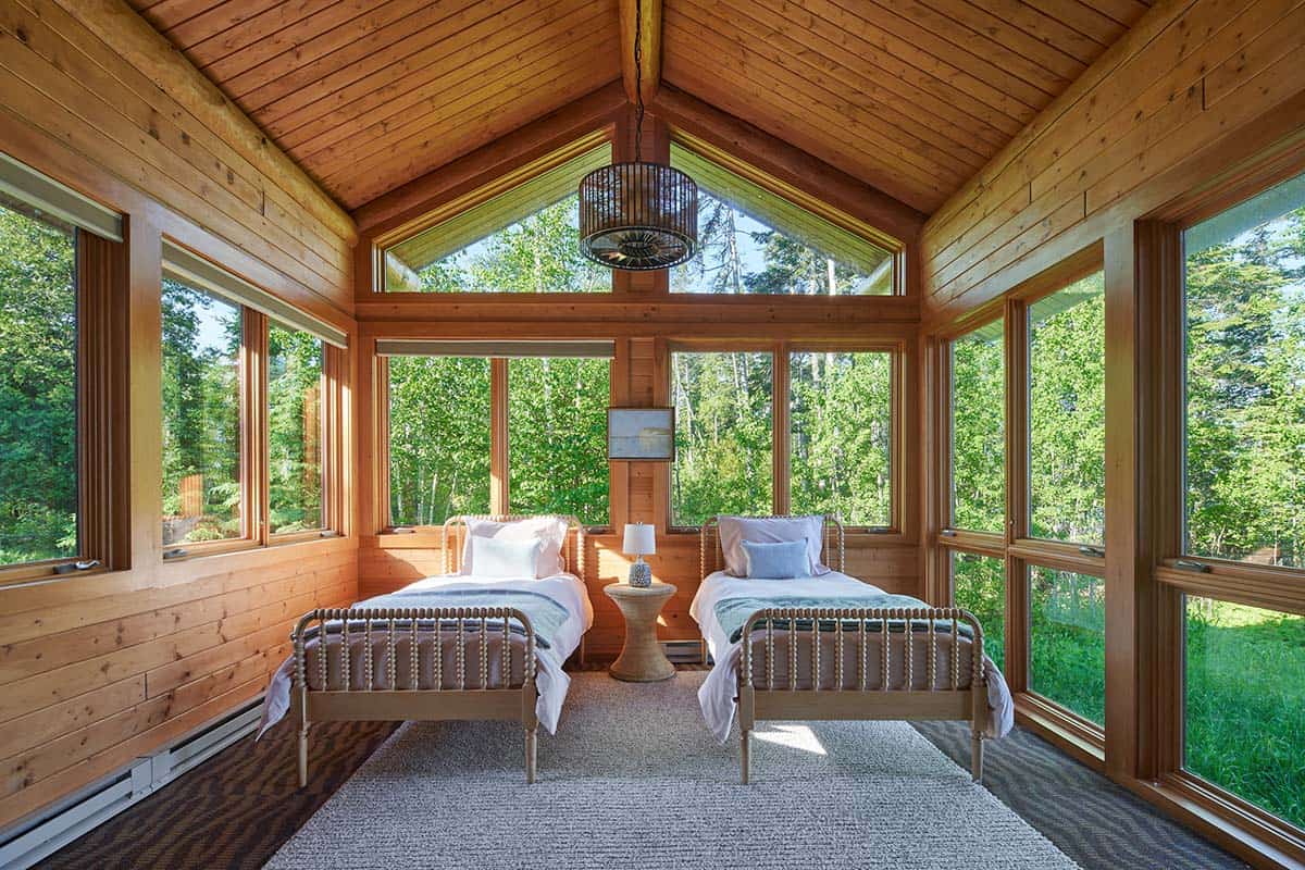 Screened porch bedroom with two twin beds and forest views