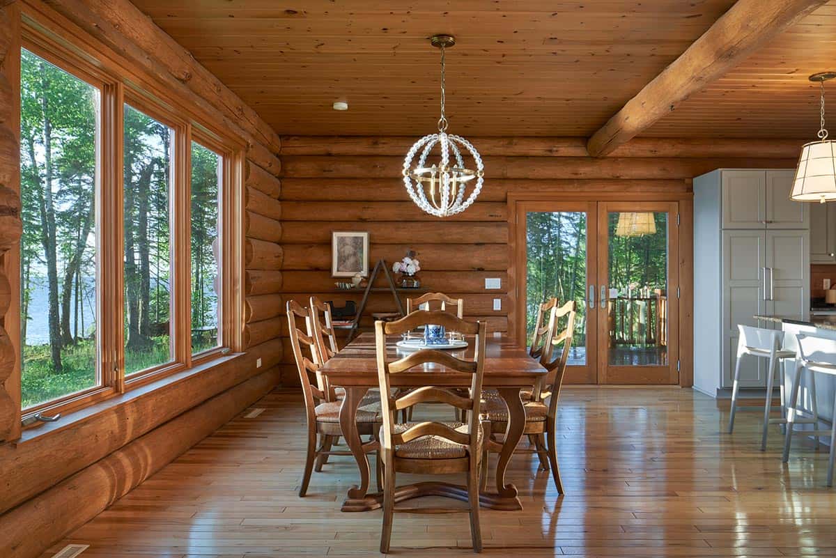 Log cabin dining room with beaded chandelier and lake views through large windows