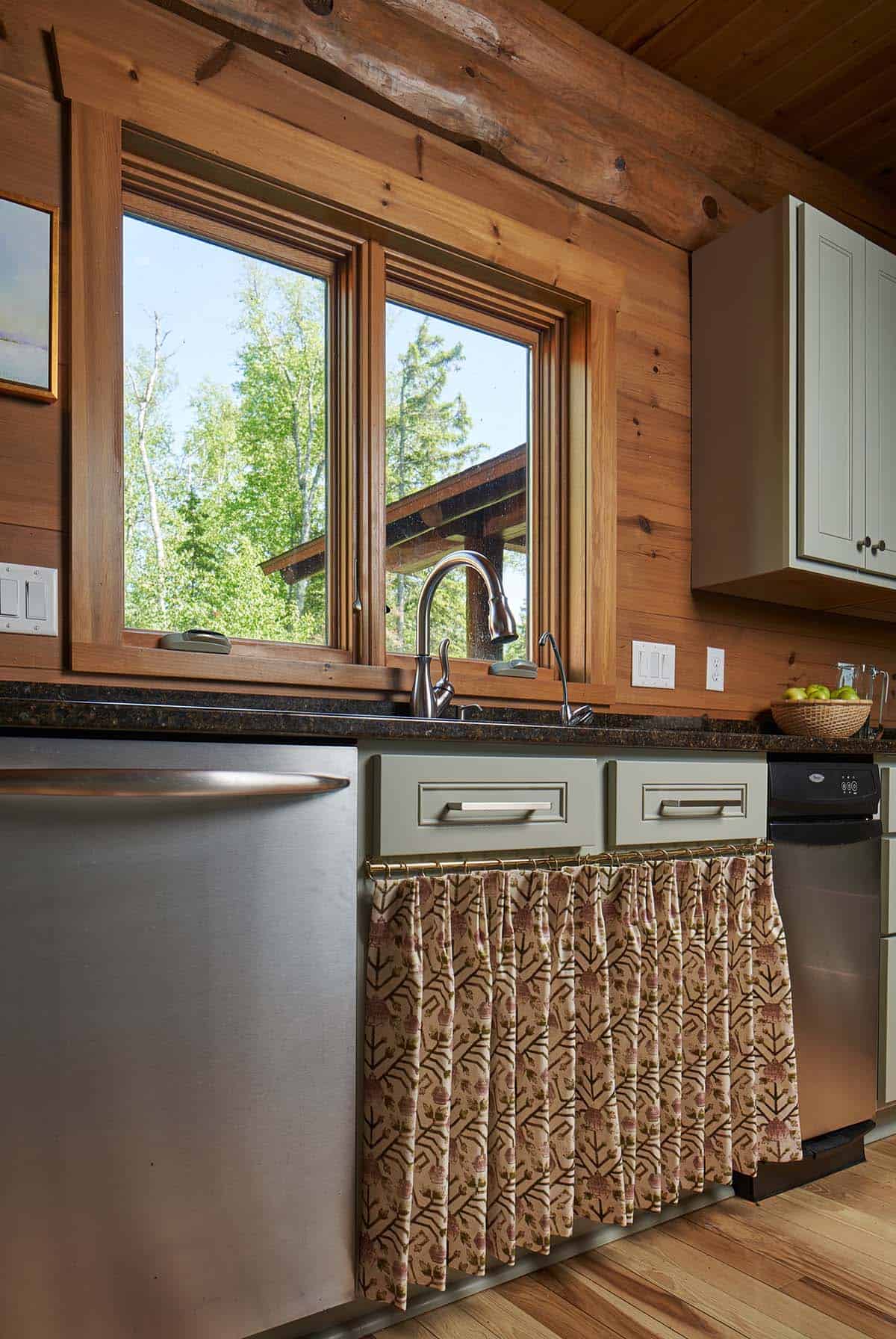 Kitchen sink area with window view, stainless faucet, and skirted cabinet