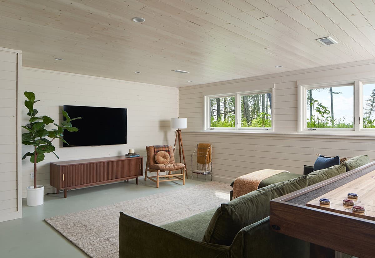 Basement lounge with wall-mounted TV, wood console, and green sofa