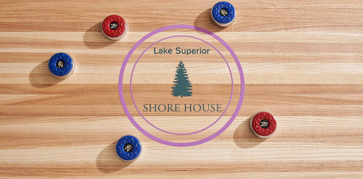 Shuffleboard table detail with "Lake Superior Shore House" logo and pucks