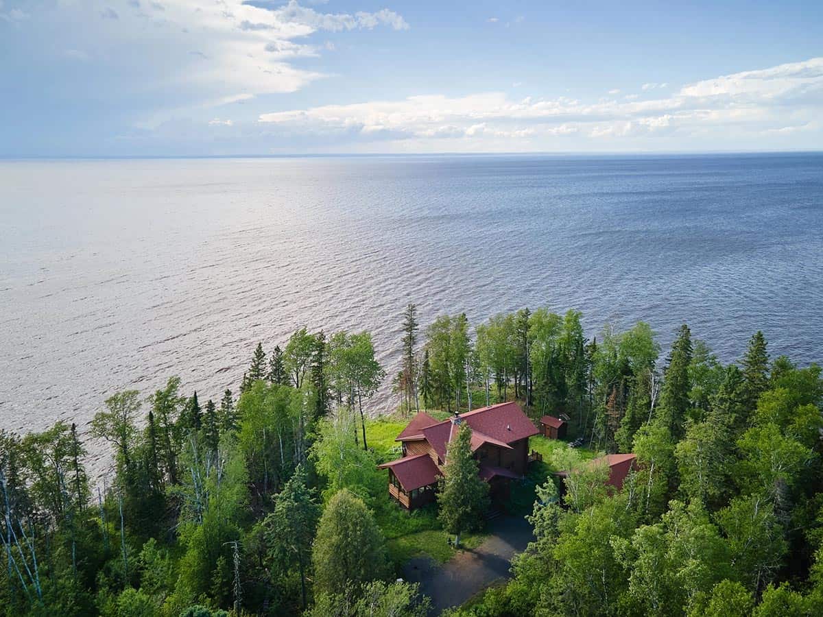 Aerial view of red-roofed cabin complex nestled in trees along Lake Superior's shoreline