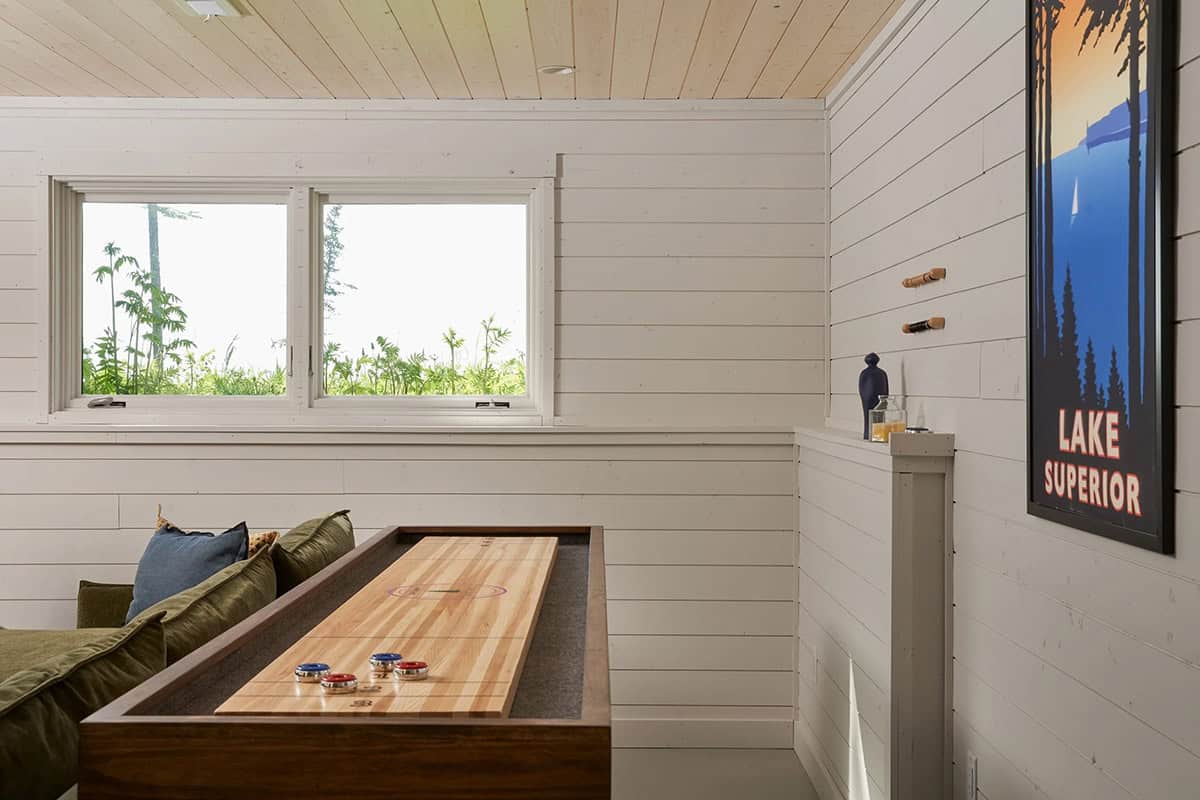 Game room corner with shuffleboard table, window, and vintage Lake Superior poster