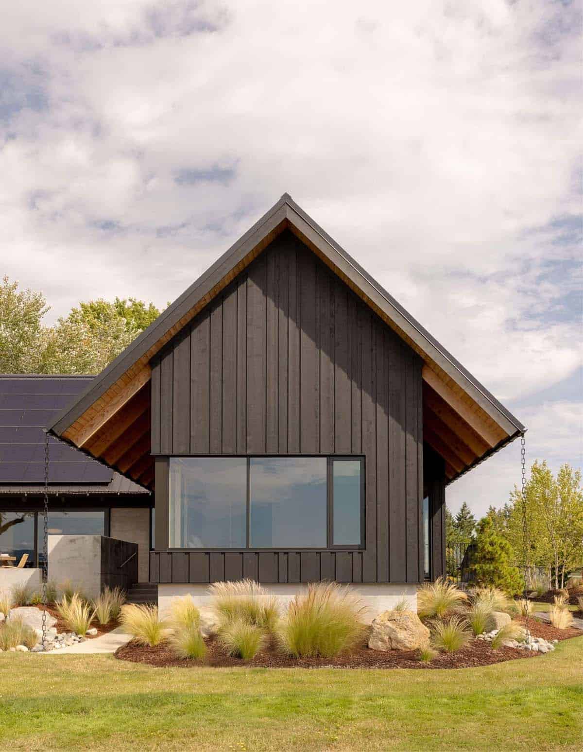 Gabled black-clad facade with exposed wood eaves and large picture window