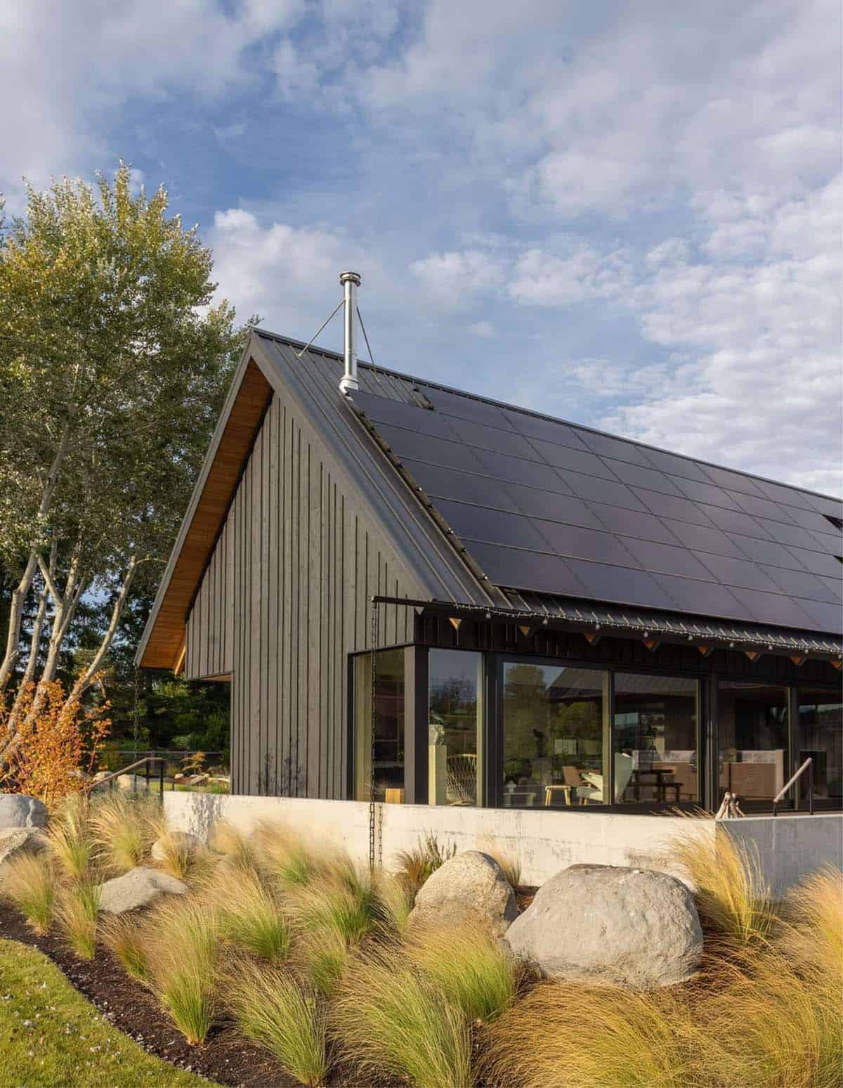 Gable end with solar panel roof, wood soffit, and glass wall overlooking patio