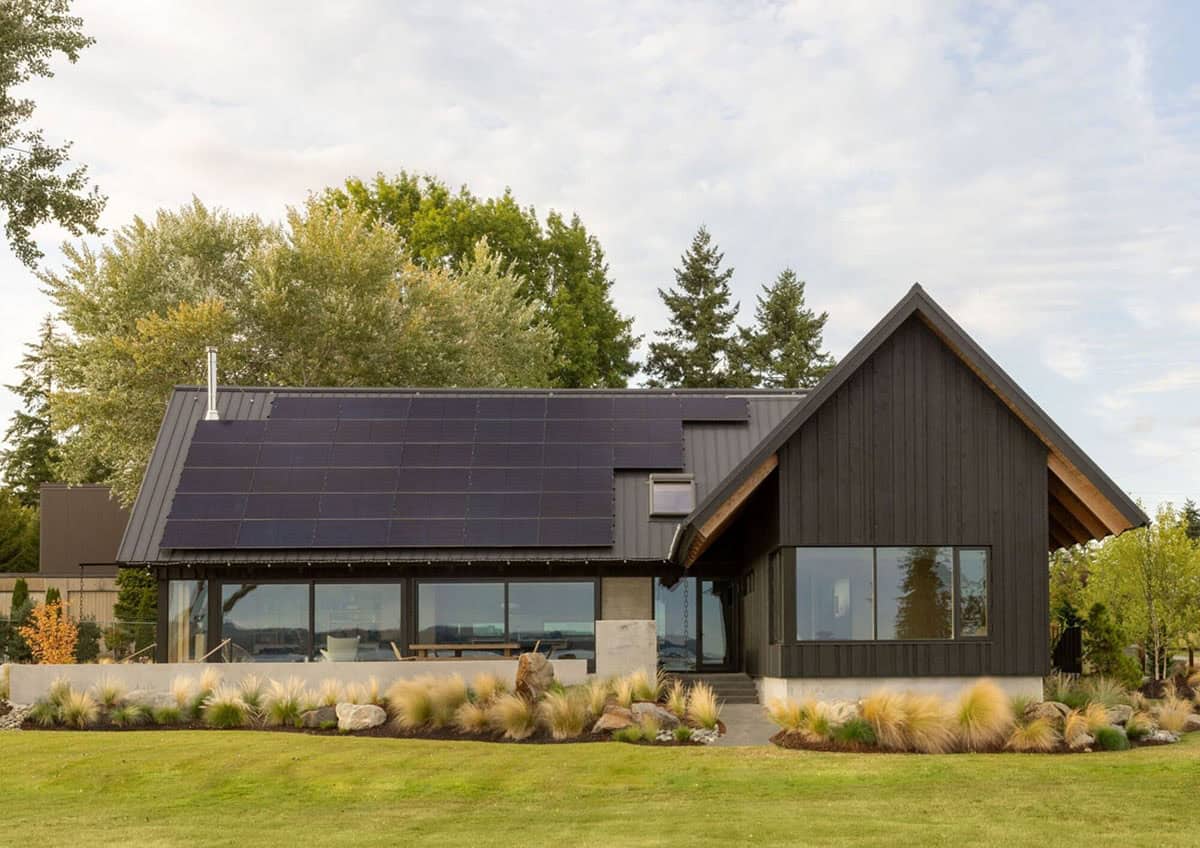 Side exterior view showing solar-paneled roof and black vertical siding