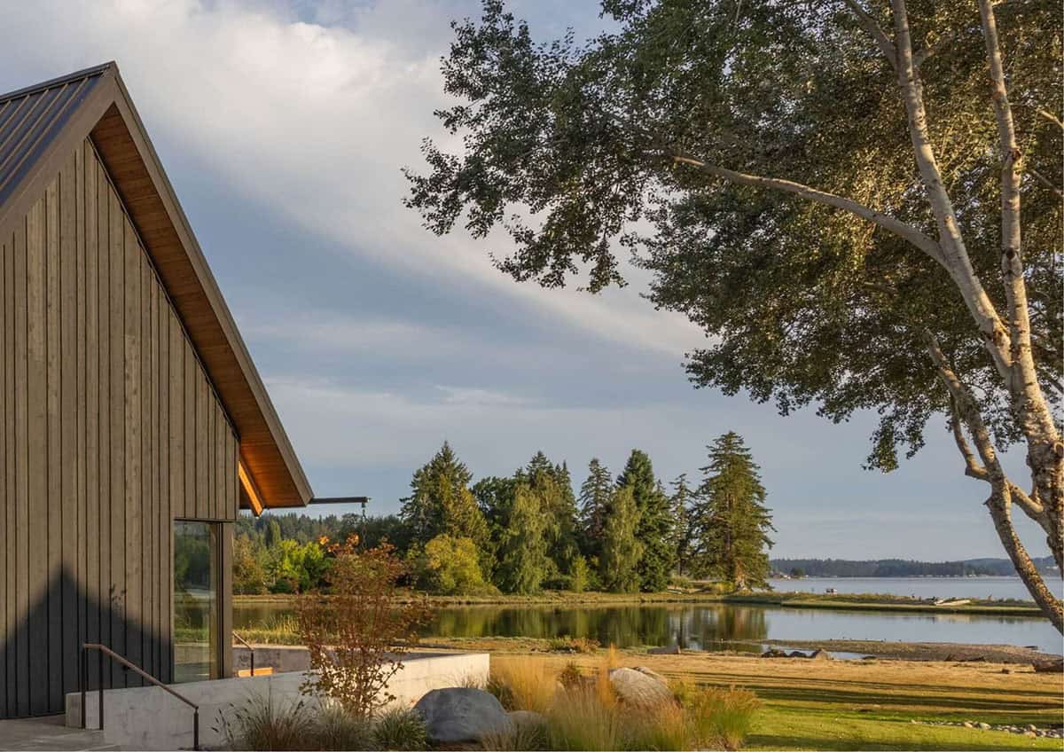 Gable end of home framed by birch trees with waterfront view beyond