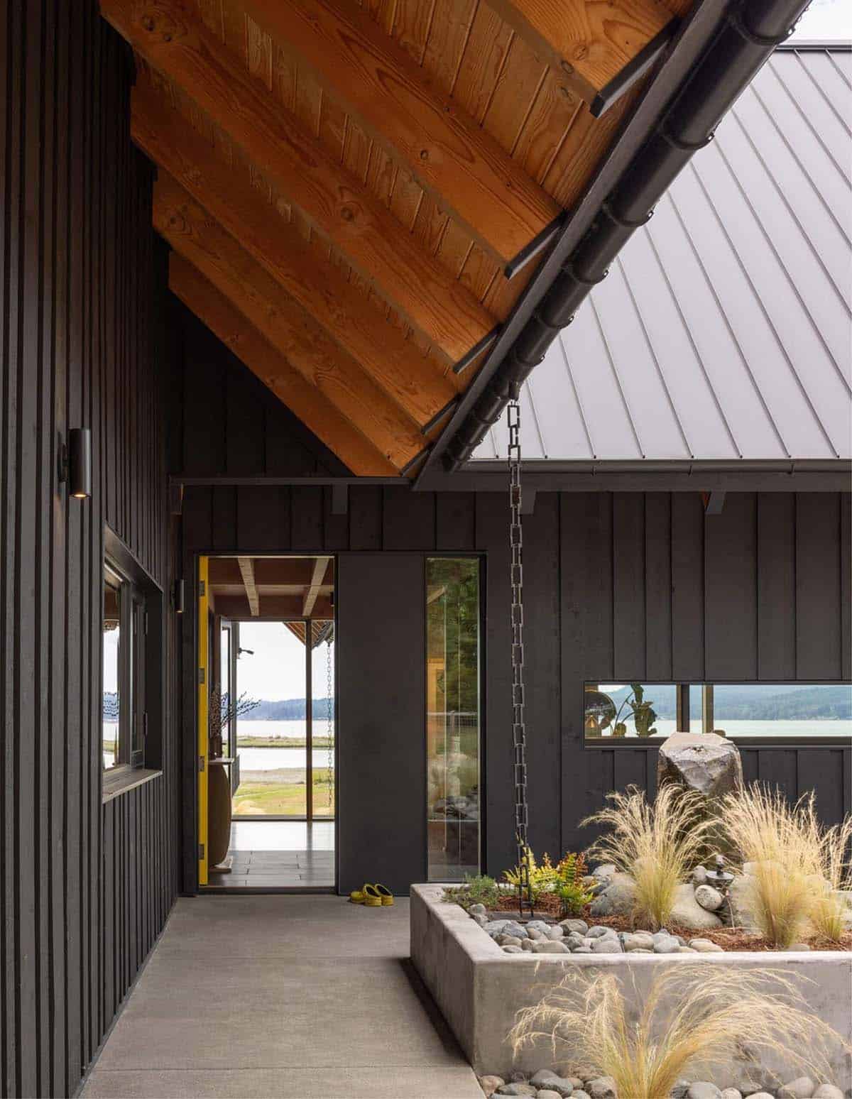 Covered entry walkway with wood ceiling, rain chain, and stone planter