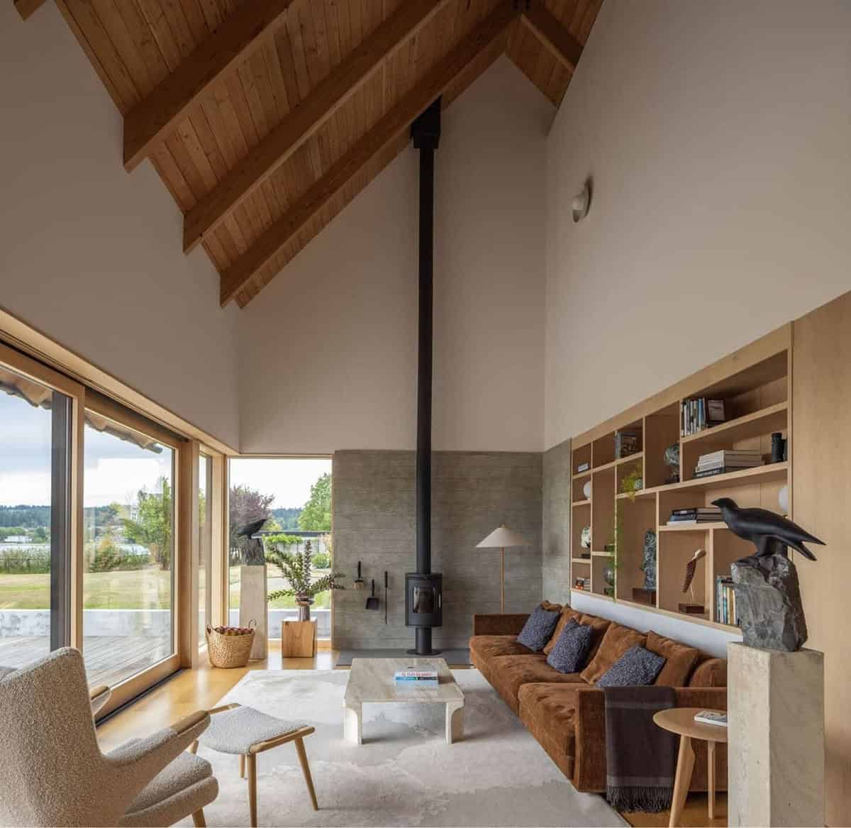 Double-height living room with wood-clad vaulted ceiling and black wood stove