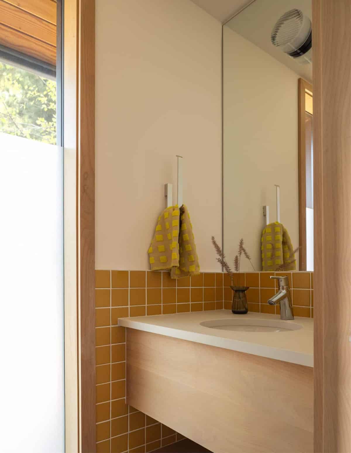 Bathroom vanity with mustard tile backsplash and wall-mounted mirror