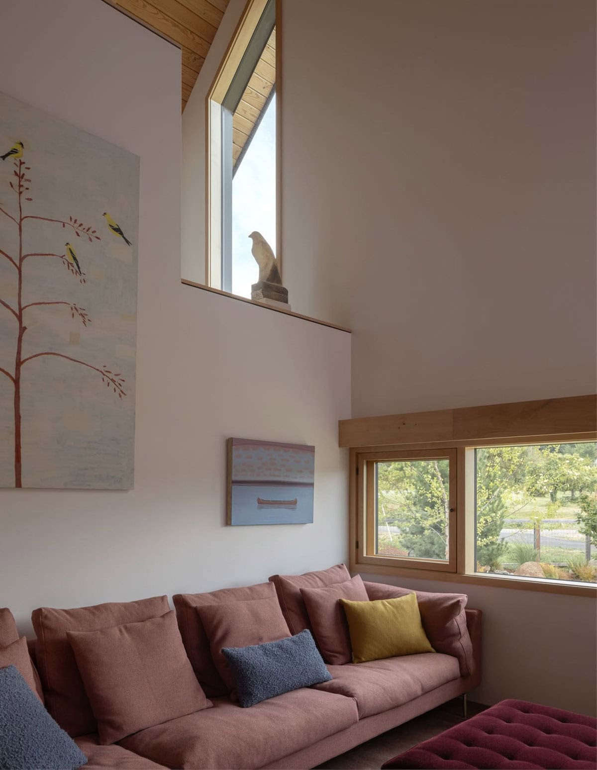 Living room corner with pink sofa, artwork, and triangular window