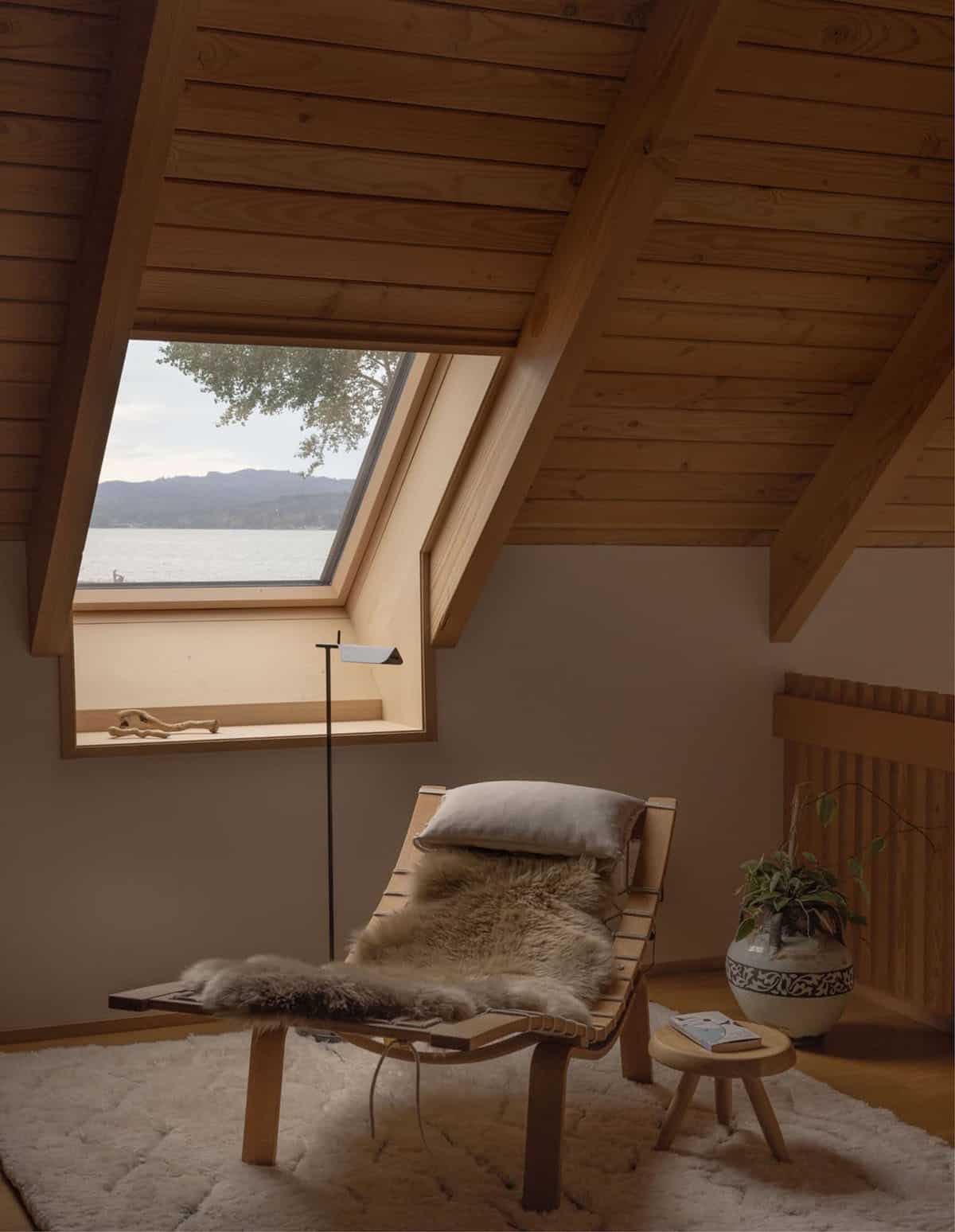 Attic lounge chair beneath skylight window with water view