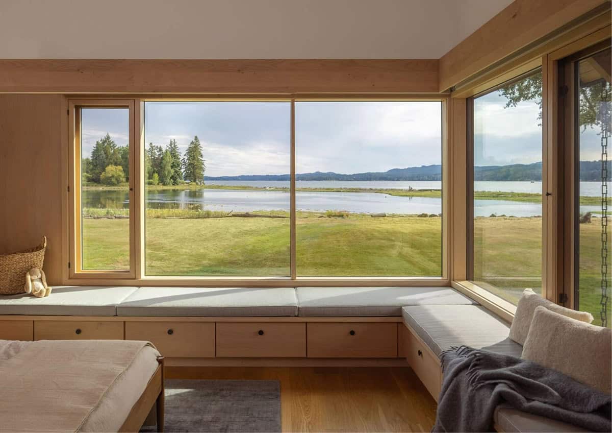 Bedroom window seat with built-in storage overlooking waterfront lawn and inlet
