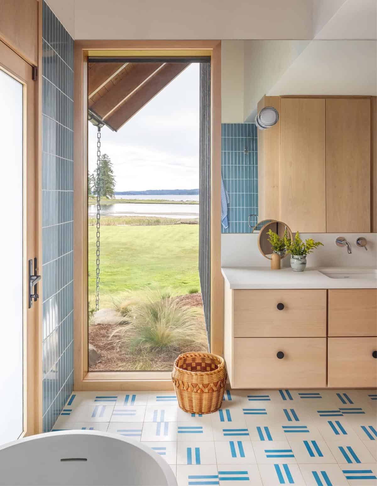 Bathroom with blue tile, freestanding tub view, and patterned floor tile