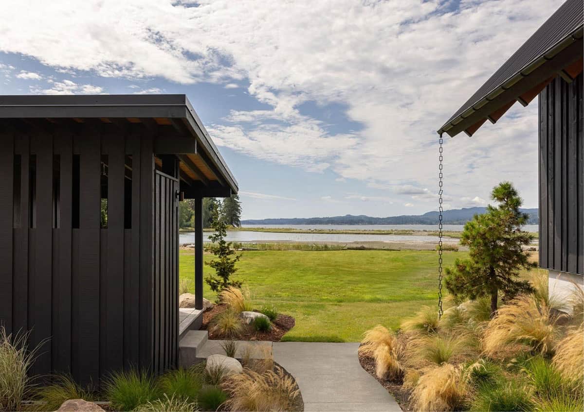 Exterior walkway between black-clad buildings with rain chain and lawn view