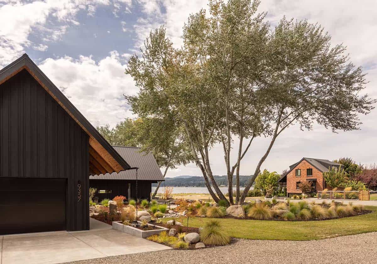 Black gabled home with garage and driveway, guest house visible across the lawn