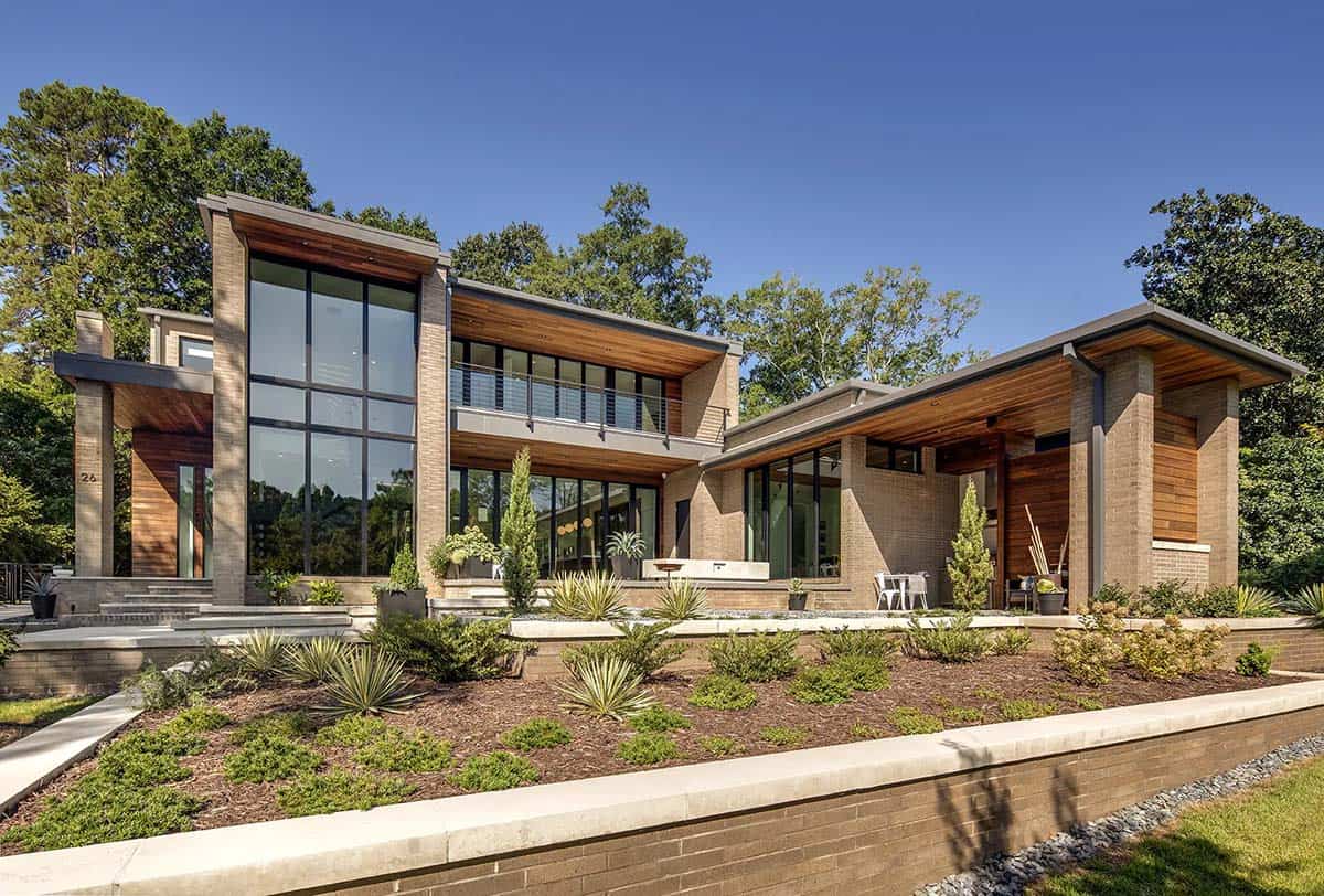Exterior view of a modern brick and wood home with two-story glass windows and desert landscaping
