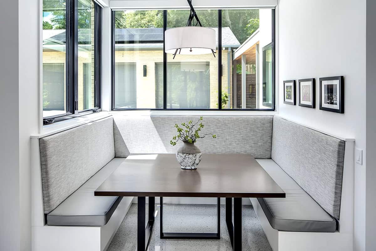 Corner breakfast nook with gray upholstered banquette seating and drum pendant light