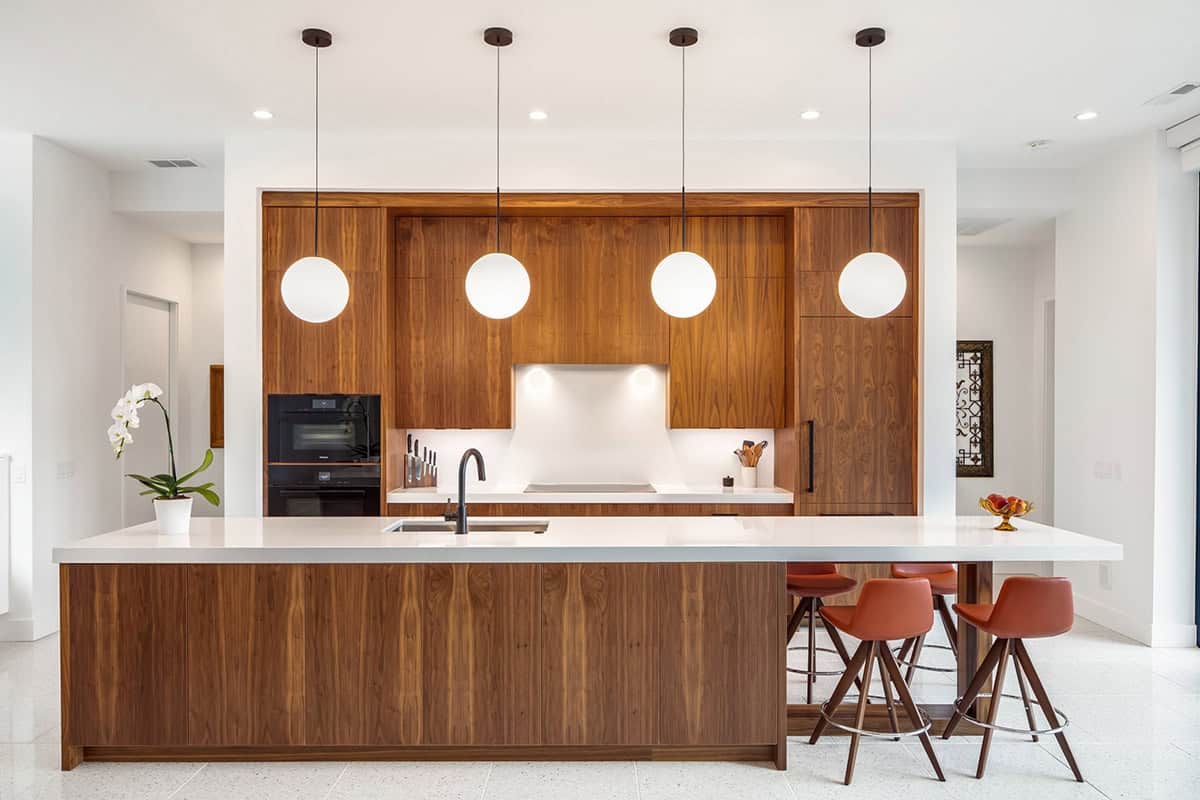 Straight-on view of walnut kitchen cabinetry with globe pendant lighting