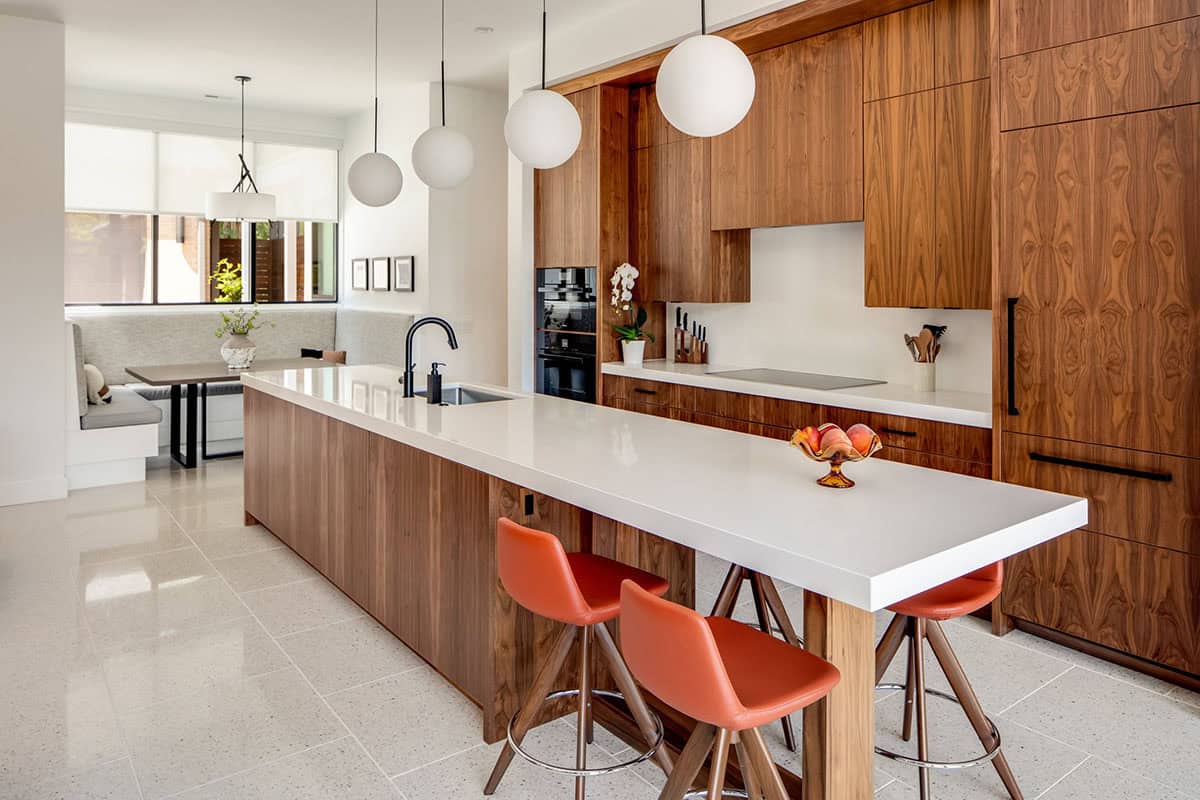 Wide kitchen view showing island, walnut cabinets, and adjoining dining nook