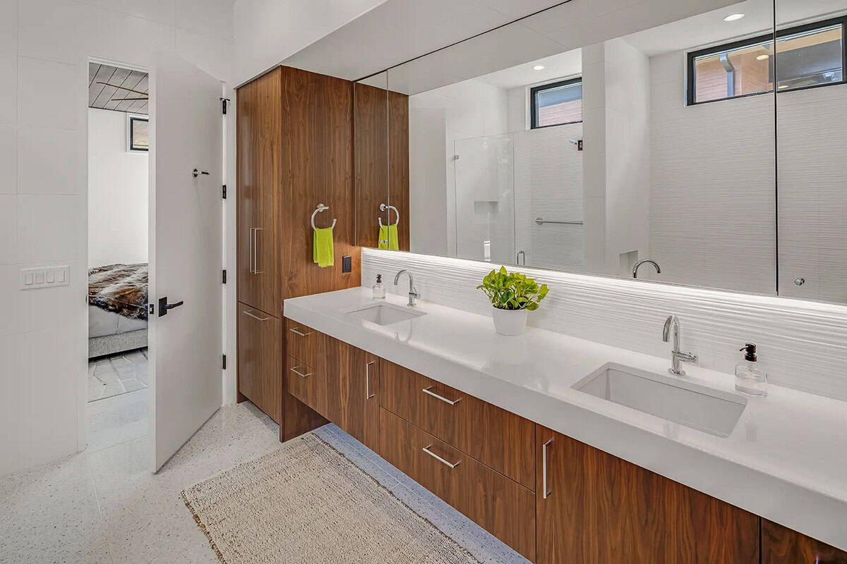 Bathroom with walnut double vanity, long mirror, and terrazzo flooring