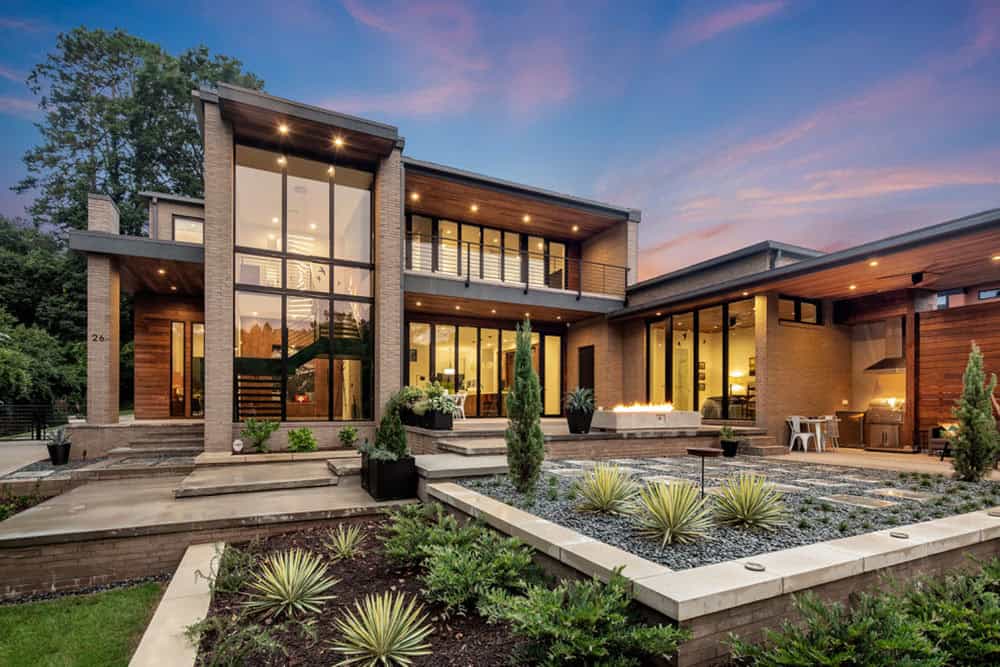 Twilight exterior view of modern home with illuminated interior and fire feature