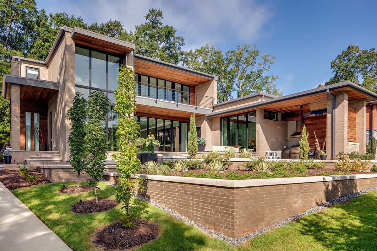 Daytime exterior of modern brick home with landscaped terraces and covered outdoor kitchen