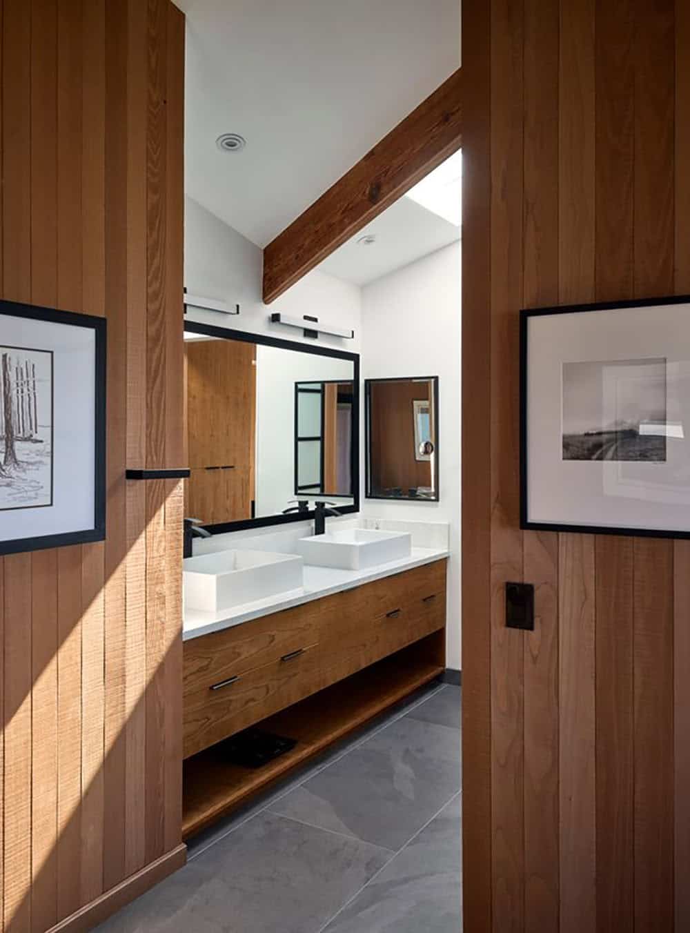 Cedar-paneled entry framing double vanity bathroom with vessel sinks and skylight