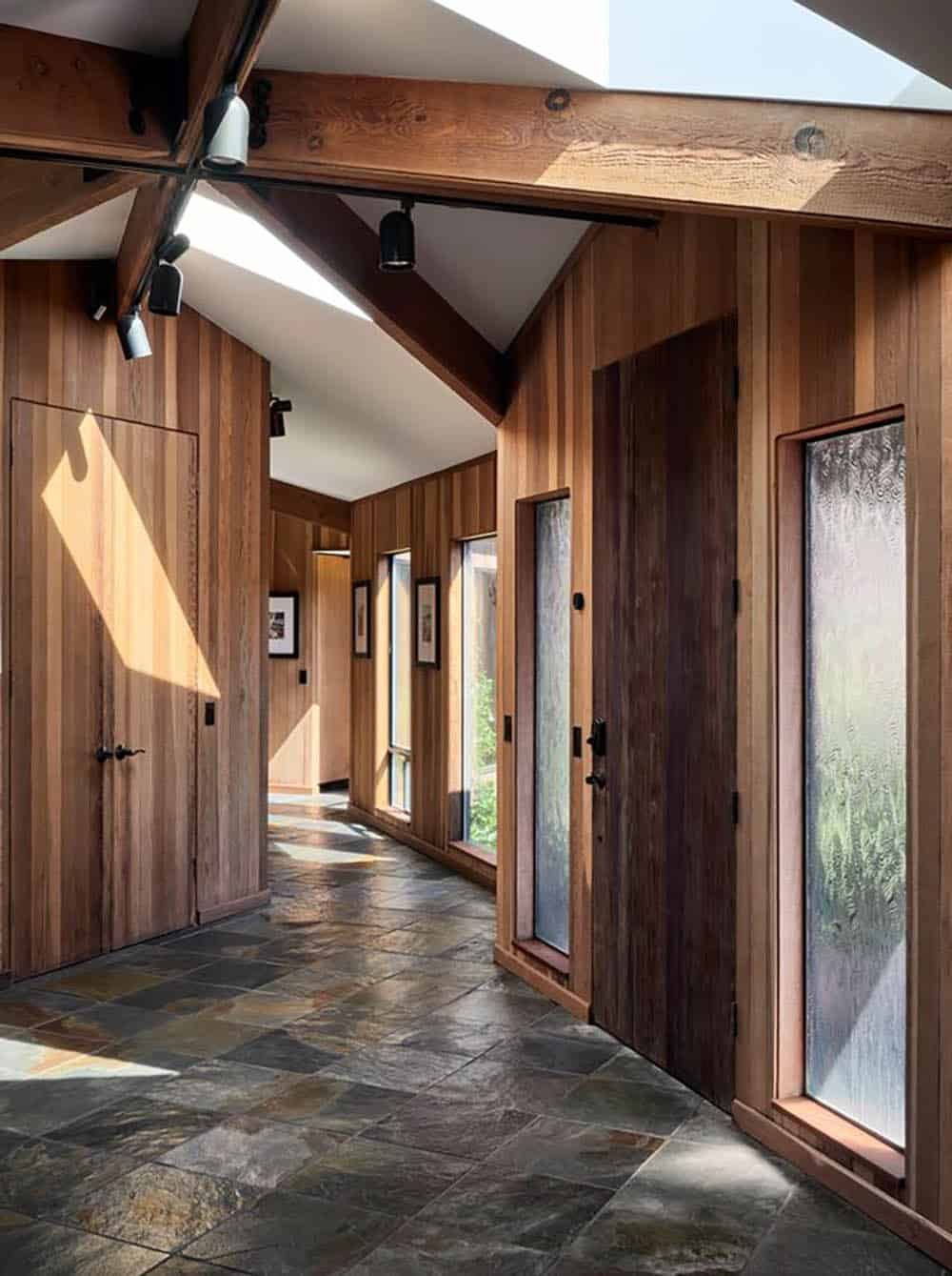 Slate-tiled hallway lined with cedar paneling and glass-paned doors