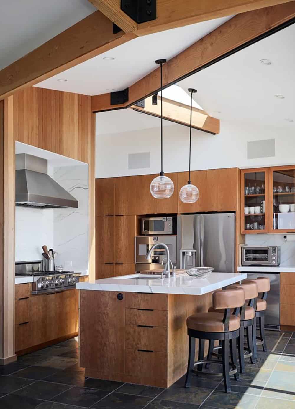 Kitchen island with glass pendant lights and skylight above cabinetry