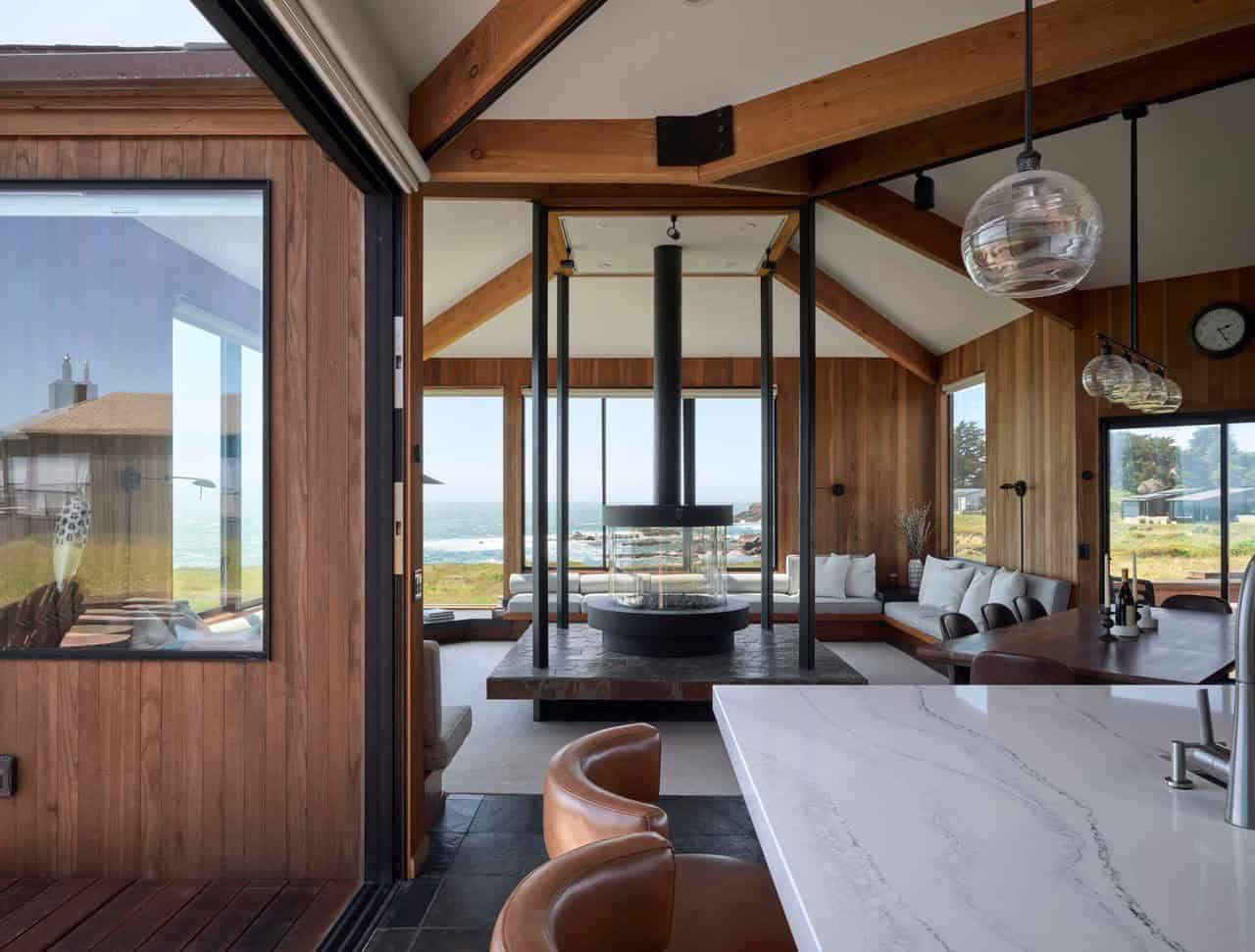 Open living and dining area with central cylindrical fireplace and ocean view