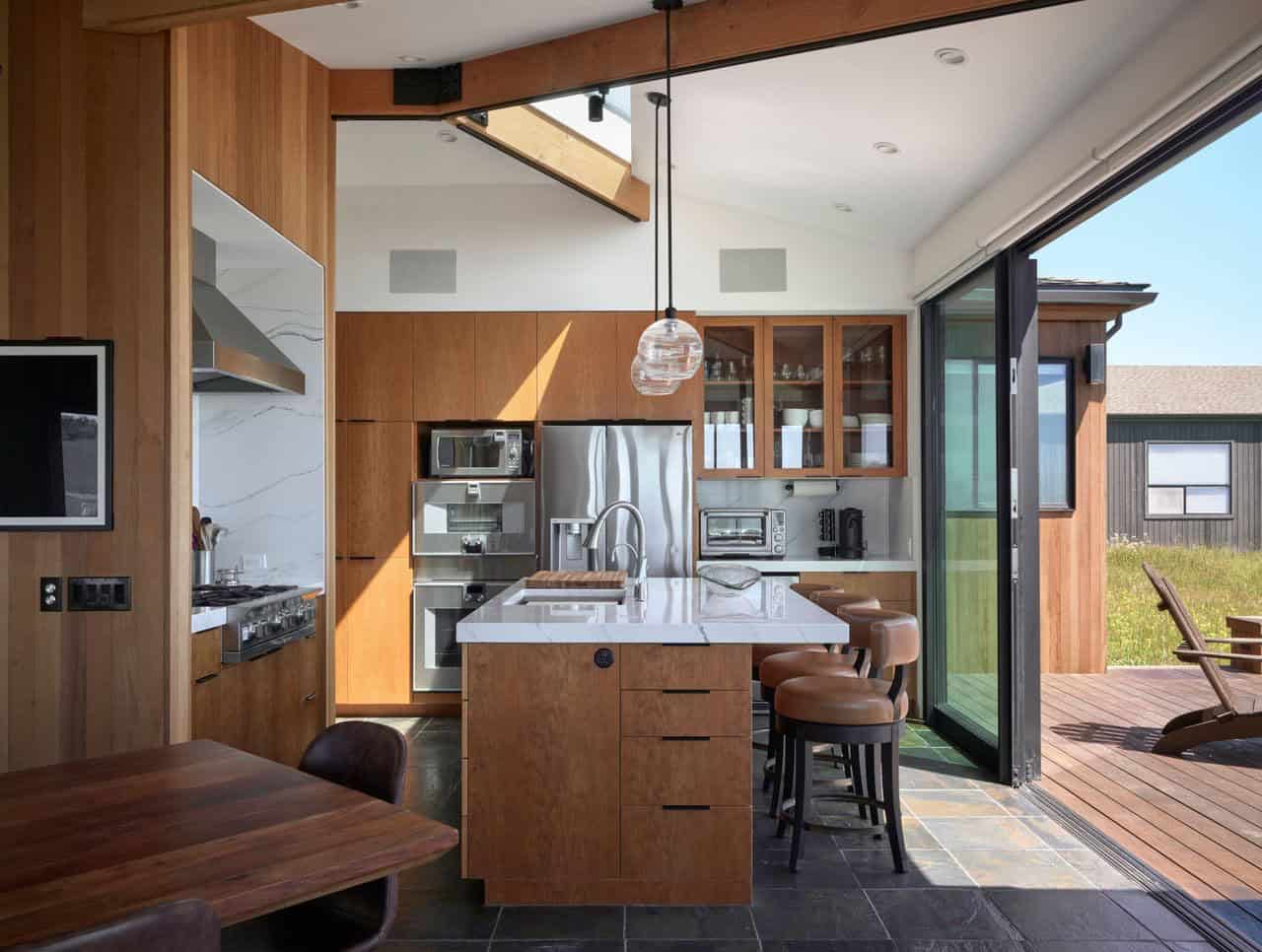 Kitchen island opening onto wood deck through folding glass doors