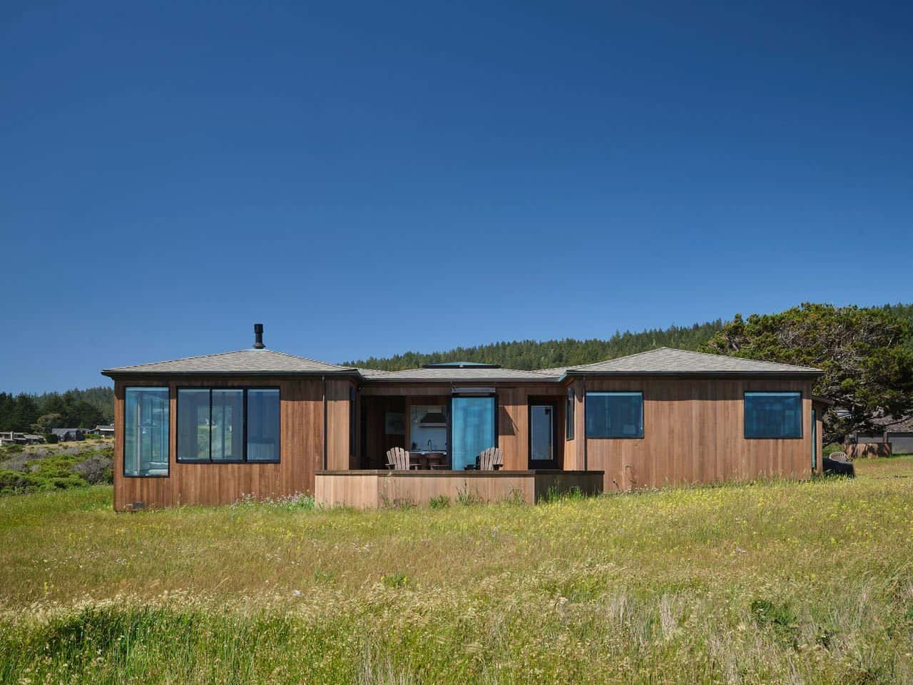 Front facade of low cedar house set in tall coastal grass