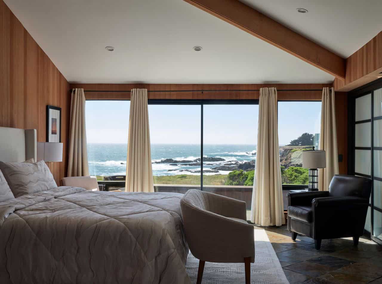 Primary bedroom with floor-to-ceiling ocean-view windows and drapery
