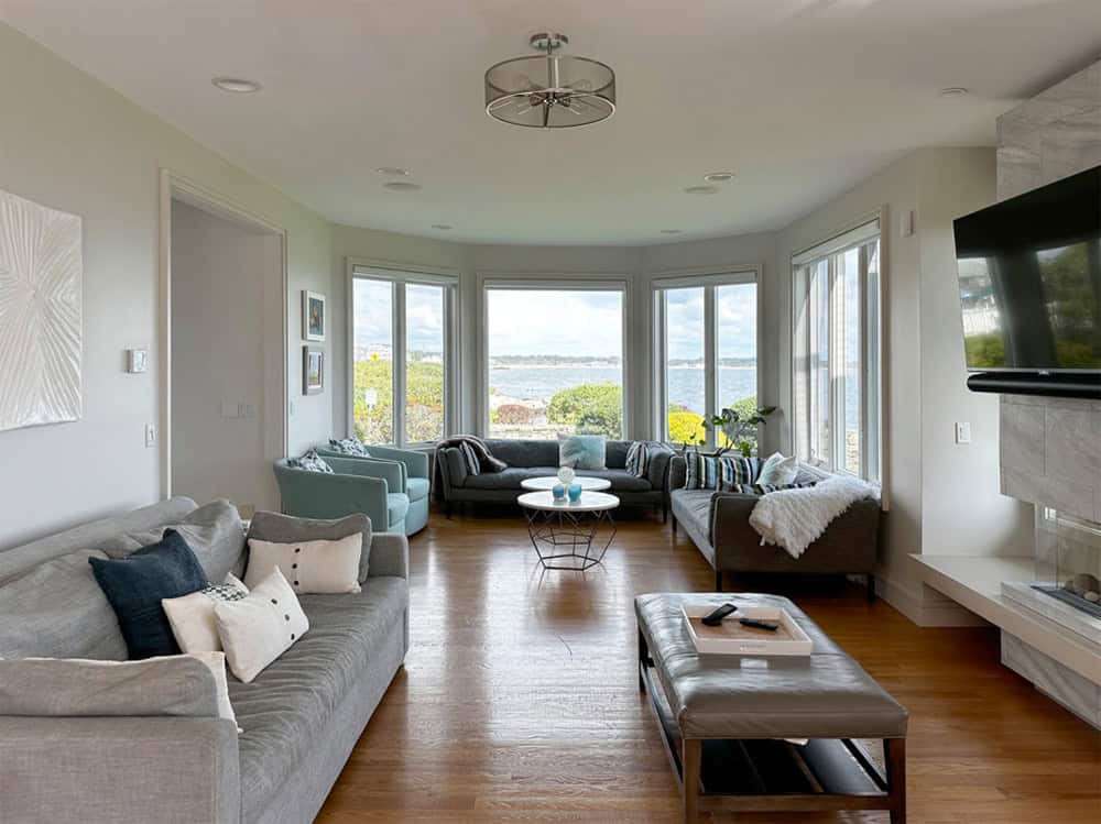 Living room with gray sectional sofa and bay window ocean view before renovation