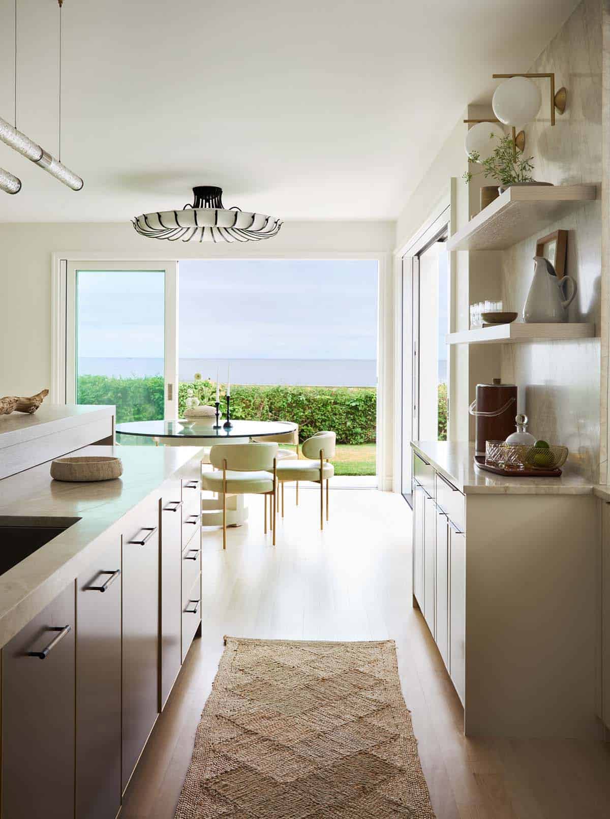 Kitchen with pass-through window overlooking round dining table and ocean