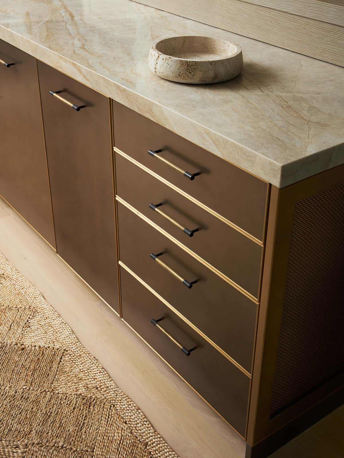 Two-tiered kitchen island detail with brass hardware and stone bowl