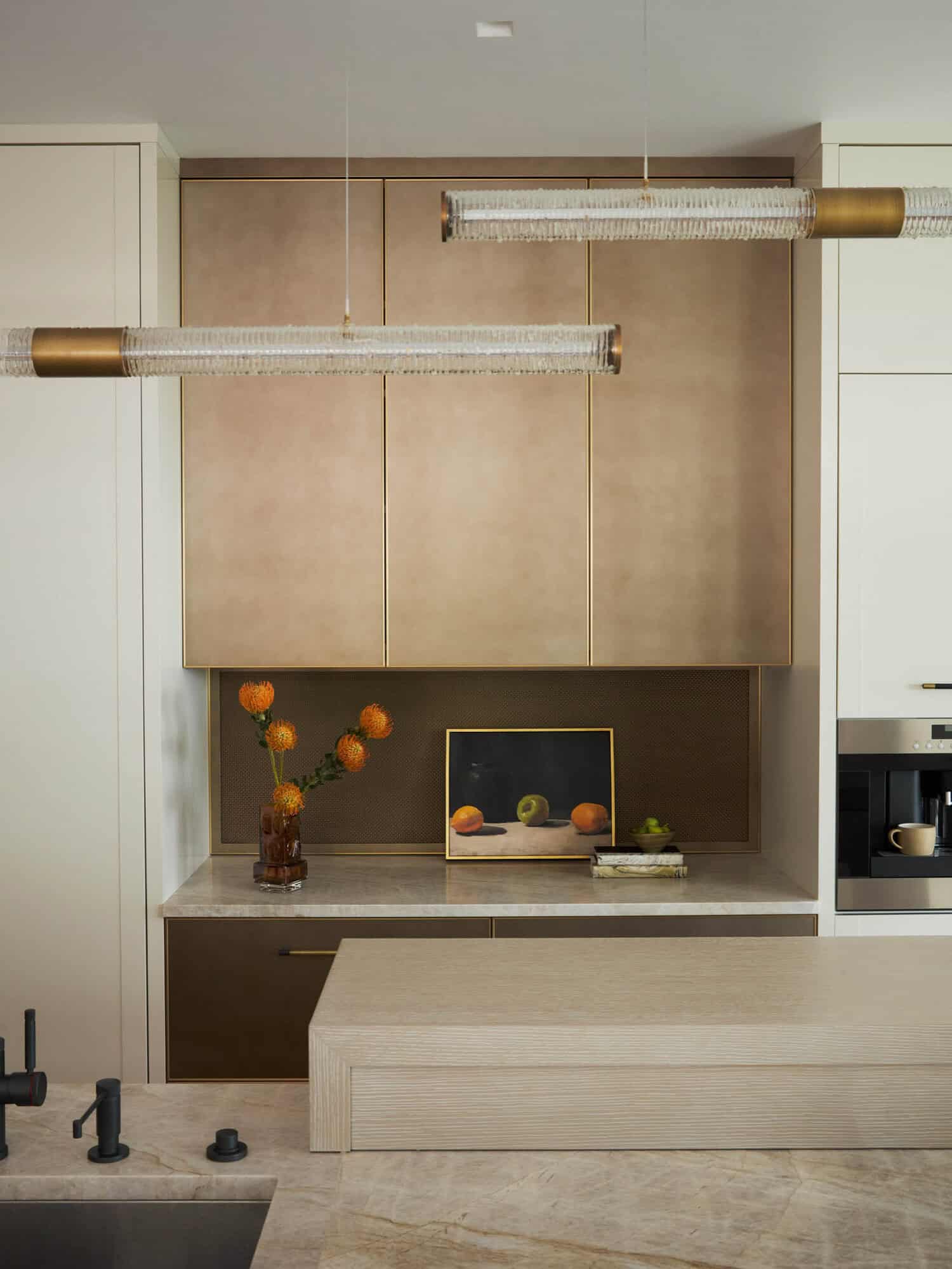 Kitchen cabinetry detail with glass pendant lights and still life art