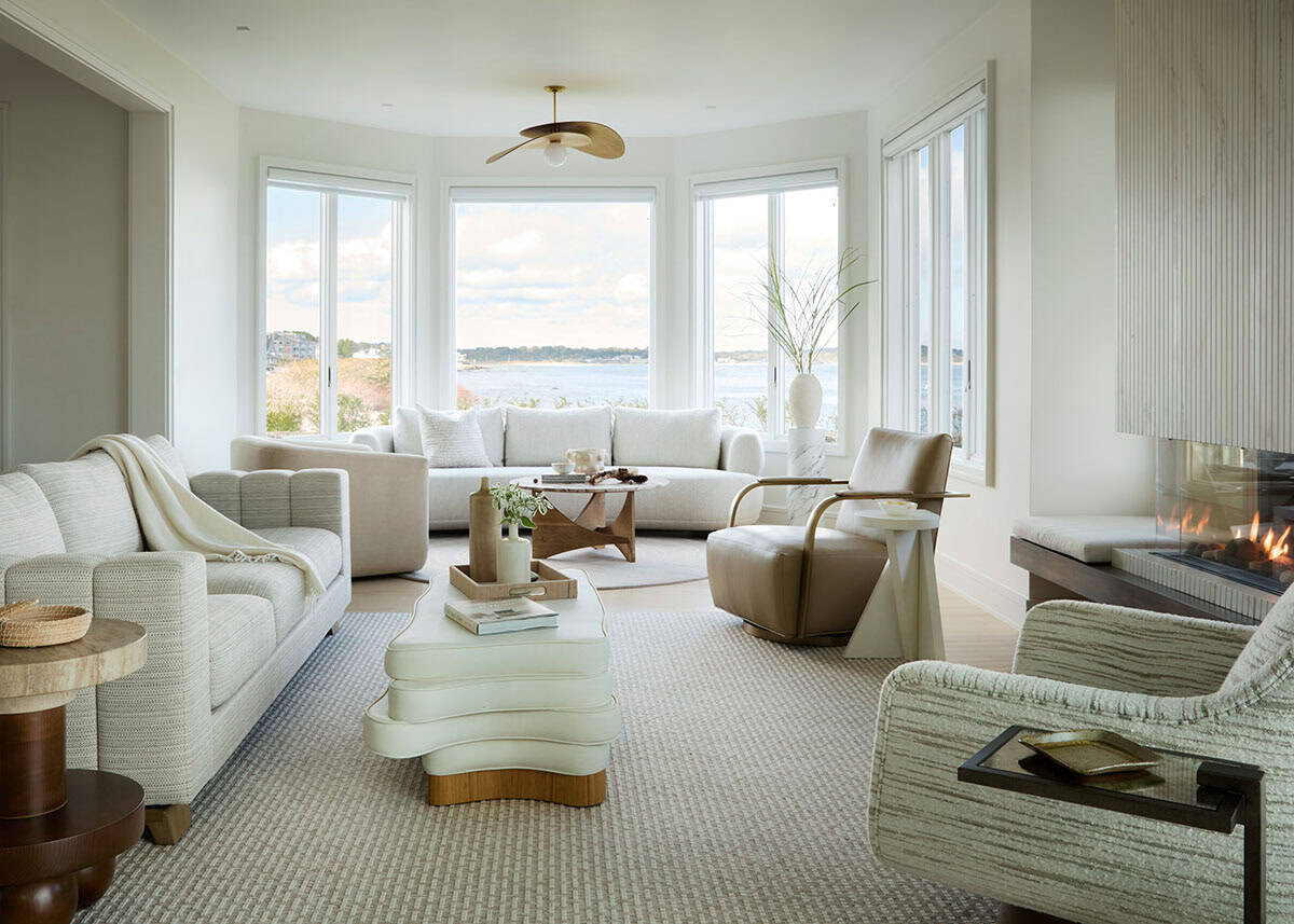 Living room with curved white sofas and ocean view through bay windows