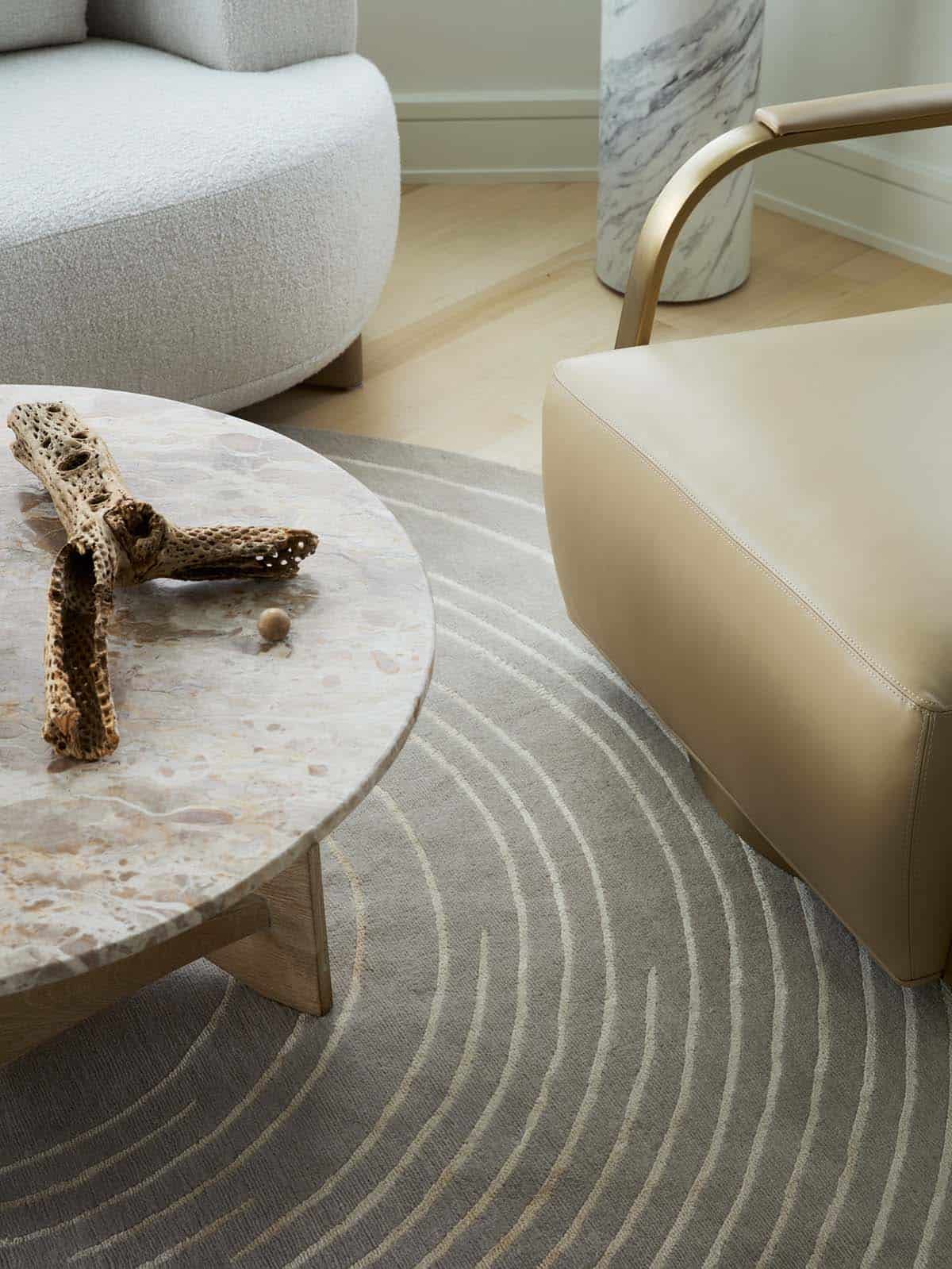 Round stone coffee table detail with driftwood and leather ottoman
