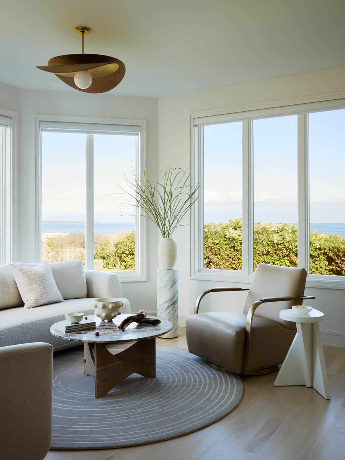 Sunroom seating area with round rug and coastal Rhode Island ocean view