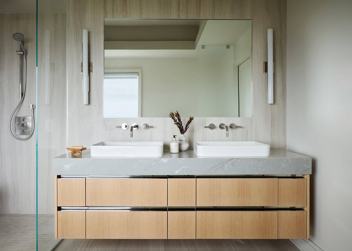 Bathroom vanity with mirror reflecting shower and window view